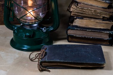 Eski yağ lambası ve masanın üzerinde yatan kitaplar. Eski s bir alev