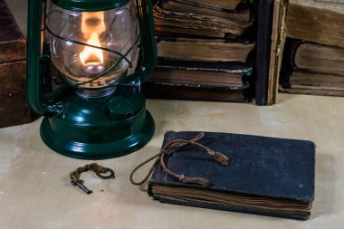 Eski yağ lambası ve masanın üzerinde yatan kitaplar. Eski s bir alev