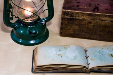 Eski yağ lambası ve masanın üzerinde yatan kitaplar. Eski s bir alev
