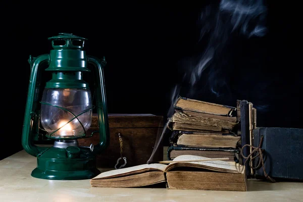 旧油灯和书躺在桌子上。古老的火焰 — 图库照片
