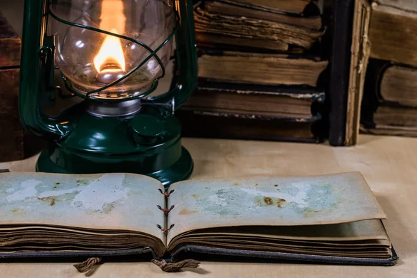 Старая масляная лампа и книги лежат на столе. Пламя от старого — стоковое фото