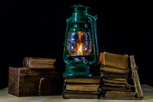 Old oil lamp and books lying on the table. A flame from an old s