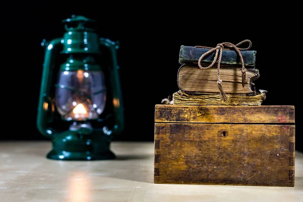 Old oil lamp and books lying on the table. A flame from an old s — Stock Photo, Image