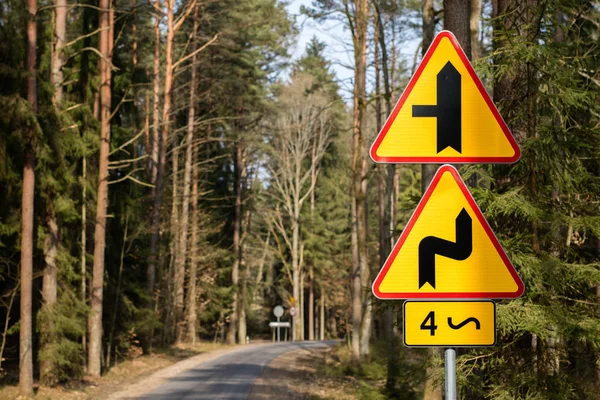 Peligrosas curvas señal de tráfico. Marcas de carretera situadas junto a un bosque — Foto de Stock