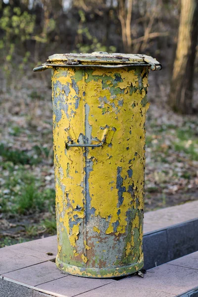 An old garbage bin. Waste trash cans set in a park between trees