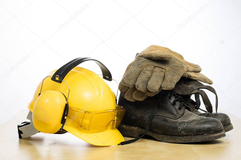 Protective helmet and work boots on a wooden table. Safety and h