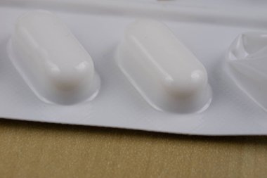 Ahşap bir masa üzerinde bir sarmalayıcı hap. Soğuk algınlığı için bir ilaç ve 