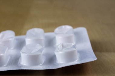 Ahşap bir masa üzerinde bir sarmalayıcı hap. Soğuk algınlığı için bir ilaç ve 