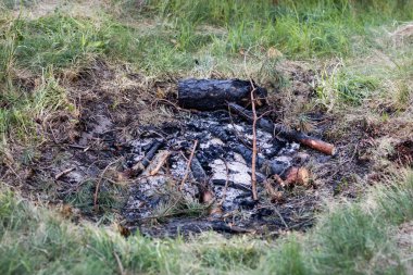 Göl kenarında ateş bir şömine. Ahşap ve kül içinde yanmış parçalar 