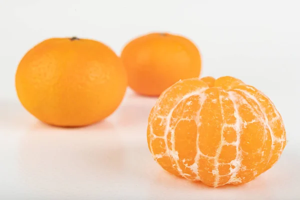 在白桌上品尝成熟的甘露。 剥皮柑橘. — 图库照片