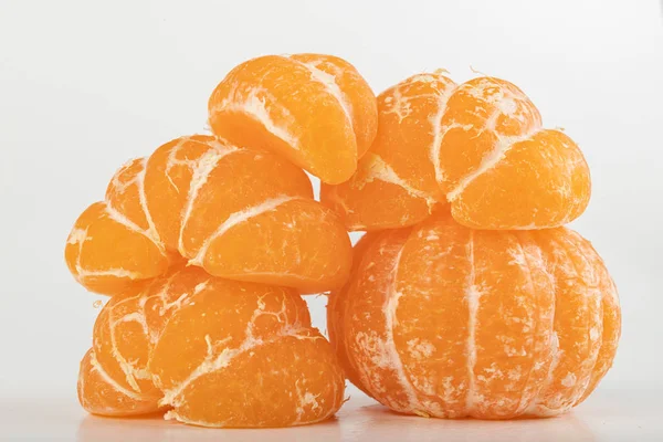 在白桌上品尝成熟的甘露。 剥皮柑橘. — 图库照片