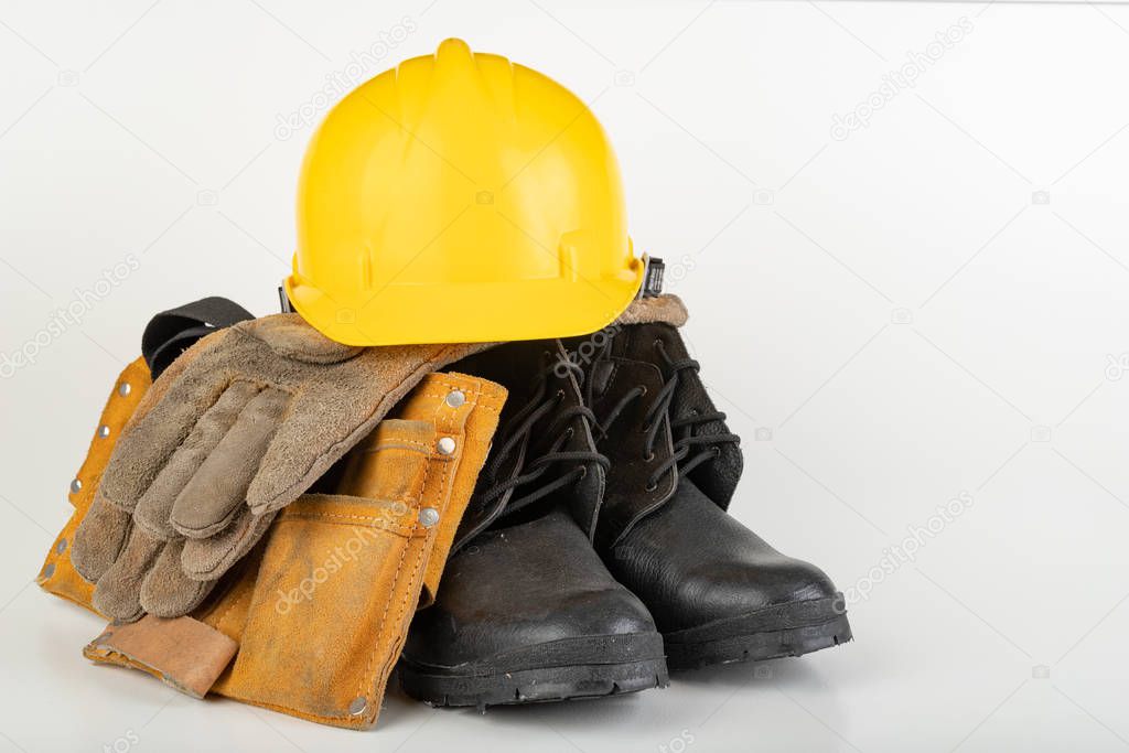 Helmet, work boots and gloves on a white table. 