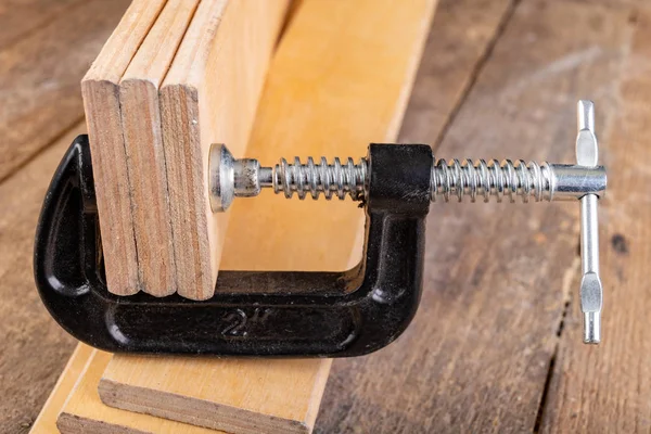 Morsetto di legno di metallo su un tavolo di officina . — Foto Stock