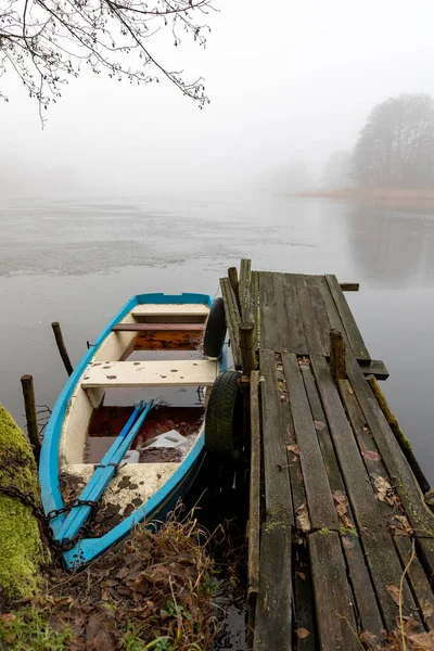 Barco de pesca amarrado a la orilla del lago. Niebla elevándose sobre el lago . —  Fotos de Stock