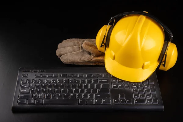 Construction helmet, work gloves on the computer keyboard. Work