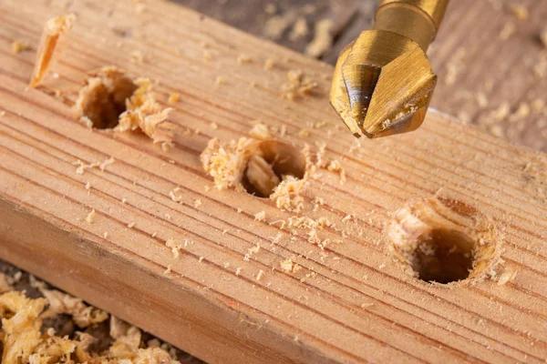 Drilling holes in a piece of wood. Countersinking the hole for w — Stock Photo, Image