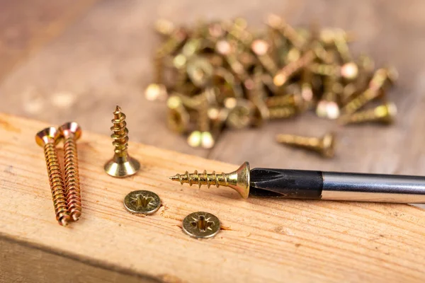 Tornillos de madera y un destornillador en un pedazo de madera. Trabajos de carpintería — Foto de Stock