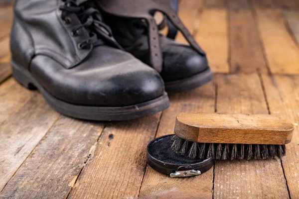 Polishing of military boots on a wooden table. Maintenance and p