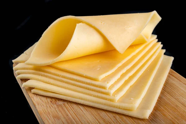 Slices of yellow cheese on a wooden board. Food from the market — Stock Photo, Image