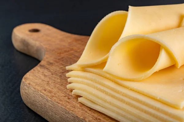 Fatias de queijo amarelo em uma tábua de madeira. Alimentos do mercado — Fotografia de Stock