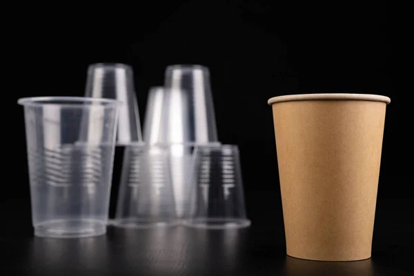 Plastic versus cardboard cups. Disposable tableware set on a tab