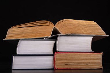 Bir yığın kitap üzerine açık, kalın bir kitap. Kapsamlı kitaplar