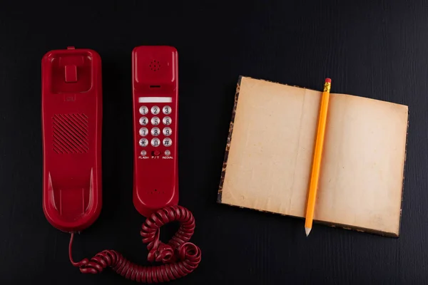Старый аналоговый телефон и блокнот на столе. Аксессуары для офиса — стоковое фото