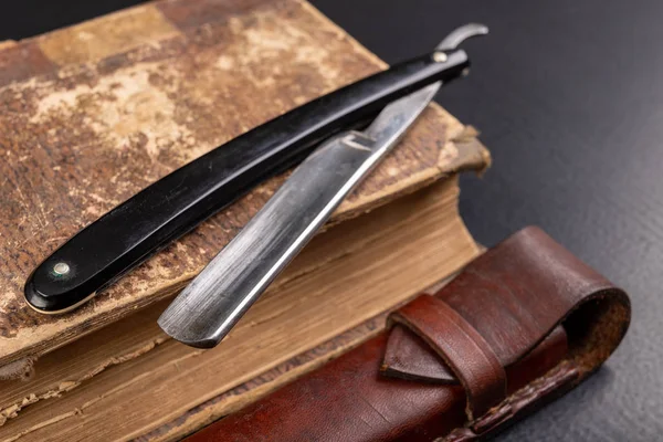 Old sharp razor and book on the table. Accessories for hairdress