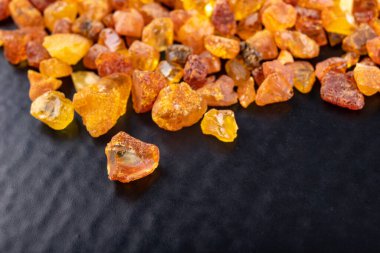 Karanlık bir masada küçük kehribar taşları. Baltık sahilinde bulunan küçük kehribar yığını. Siyah arkaplan.