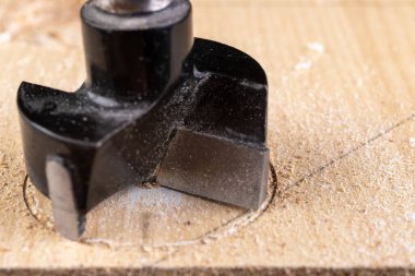 Yonga tahtasında özel bir matkapla delmek. Marangozluk atölyesinde çalışıyorum. Hafif arkaplan.