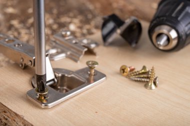 Mobilya menteşelerinin yonga tahtasına yerleştirilmesi. Atölyede küçük marangozluk işi. ışık arkaplanı.