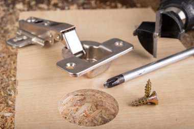 Mobilya menteşelerinin yonga tahtasına yerleştirilmesi. Atölyede küçük marangozluk işi. ışık arkaplanı.