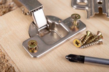 Mobilya menteşelerinin yonga tahtasına yerleştirilmesi. Atölyede küçük marangozluk işi. ışık arkaplanı.