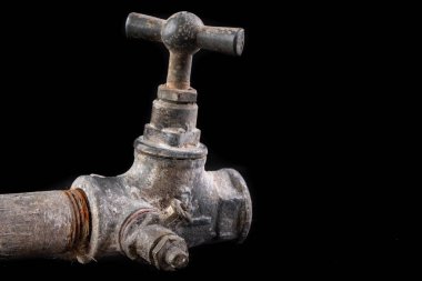 Eski, kirli metal su musluğu. Tesisatçı için aksesuarlar ve aletler. Koyu arkaplan.