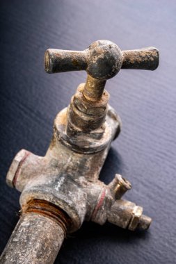 Eski, kirli metal su musluğu. Tesisatçı için aksesuarlar ve aletler. Koyu arkaplan.