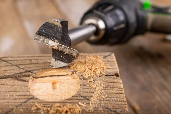 Drilling in raw wood. Drill bit for large holes. Place - carpentry workshop.