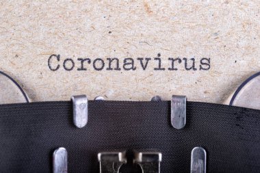 Daktilo yazı tipiyle yazılmış Coronavirus kelimesi. Gri kağıda eski usul bir yazı. Gri arkaplan.