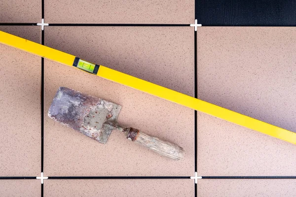 Depoya gri fayanslar seriyorum. Havan topu yapmak için eski bir ruh seviyesi ve mala. Koyu arkaplan.