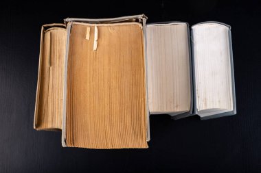 Bir sıra kağıt yayınının arka planına karşı açık, geniş bir kitap. Bir yığın eski kitap ve rehber. Koyu arkaplan.