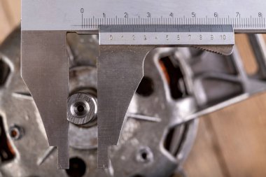 İpliği analog kalibre ile ölçüyorum. Atölyede ölçü işi. Hafif arkaplan.