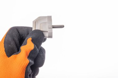 Fiş eldivenli bir elde tutuluyor. Evdeki elektrikli aksesuarlar. Koyu arkaplan.