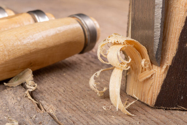 Work with a carpenter's chisel in pine wood. Small carpentry work in the home workshop. Light background.