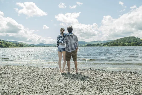 Homme et femme debout tenant la main sur le rivage — Photo