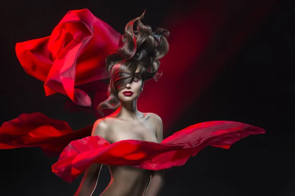 Retrato feminino com um penteado de vanguarda e os panos voadores de tecido vermelho em um fundo preto-vermelho — Fotografia de Stock