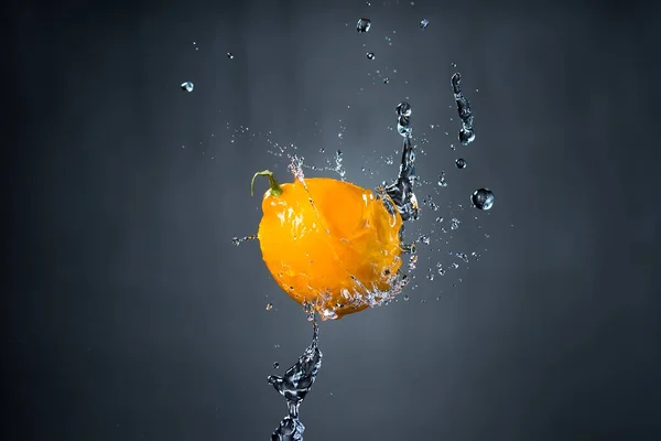 Лимон и брызги воды на сером фоне — стоковое фото