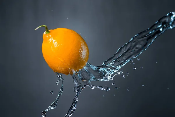 Zitrone und Wasserspritzer auf grauem Hintergrund — Stockfoto
