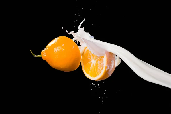 Dos mitades de limón y salpicadura de leche aislada sobre fondo negro —  Fotos de Stock