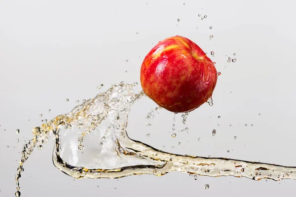 Manzana roja y salpicadura de jugo en fondo blanco —  Fotos de Stock