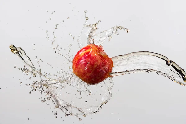 Красное яблоко и брызги сока на белом фоне — стоковое фото