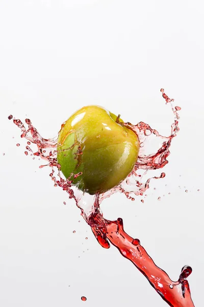 Manzana verde y salpicadura de jugo rojo en fondo blanco —  Fotos de Stock